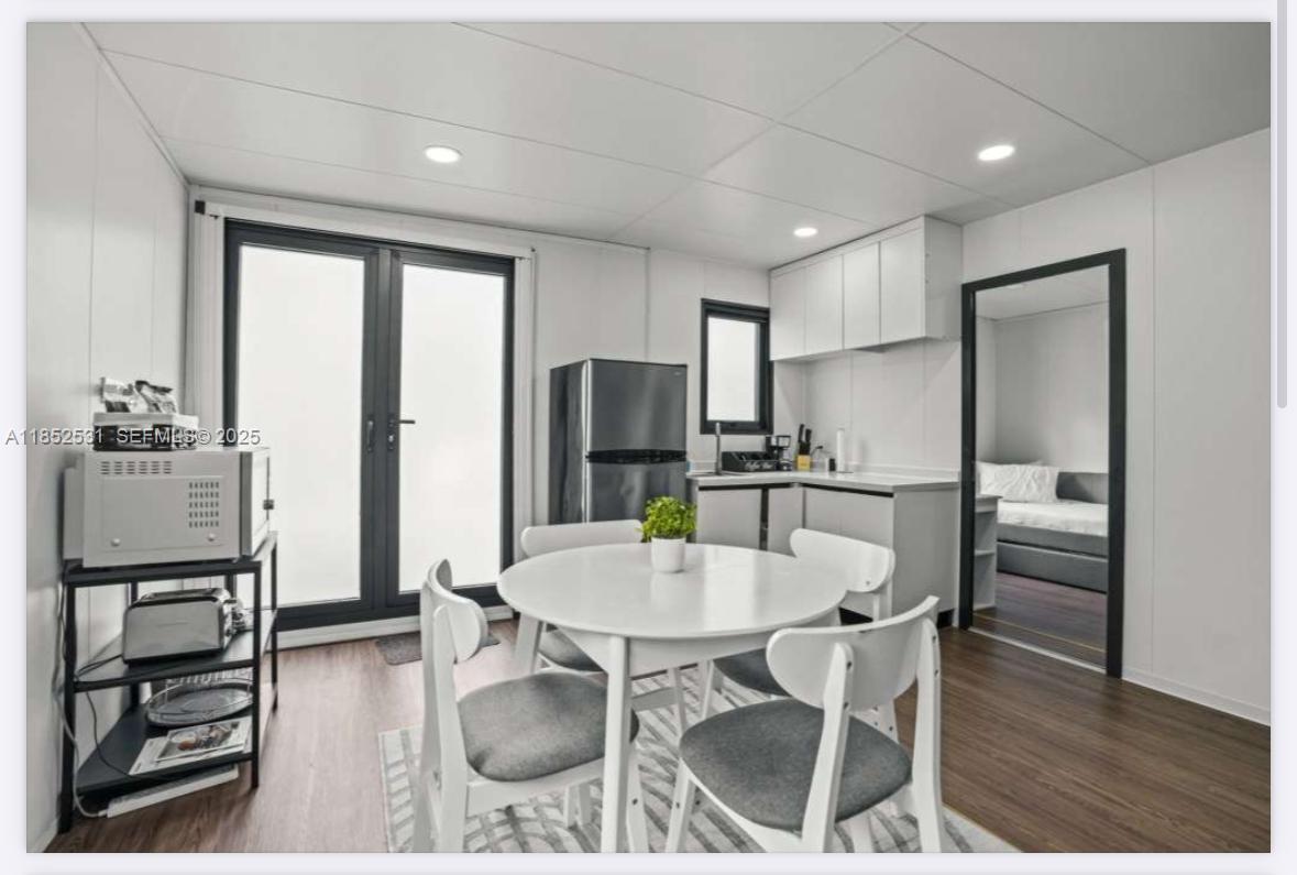 0 Golden Gate Estate, Unit 46 Naples, FL 34120 - Photo 14 of 16 a kitchen with stainless steel appliances kitchen island granite countertop a refrigerator a stove a microwave oven with a dining table and chairs with wooden floor