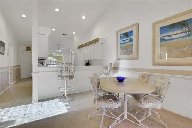 a kitchen with stainless steel appliances kitchen island granite countertop a table chairs and a refrigerator