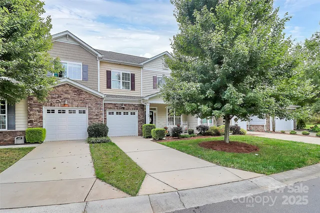 a front view of a house with a garden and trees