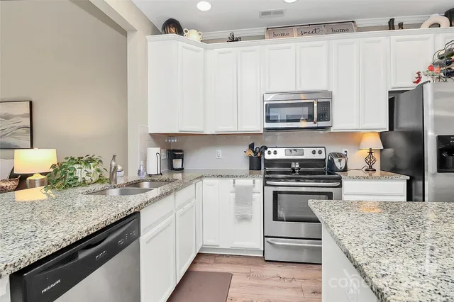 a kitchen with granite countertop a sink stove and refrigerator