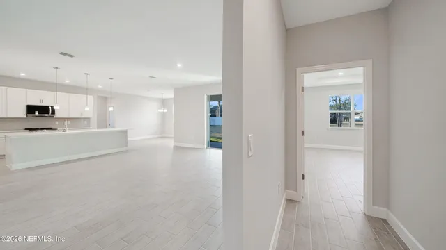 a view of a hallway with kitchen island white cabinetry and wooden floor