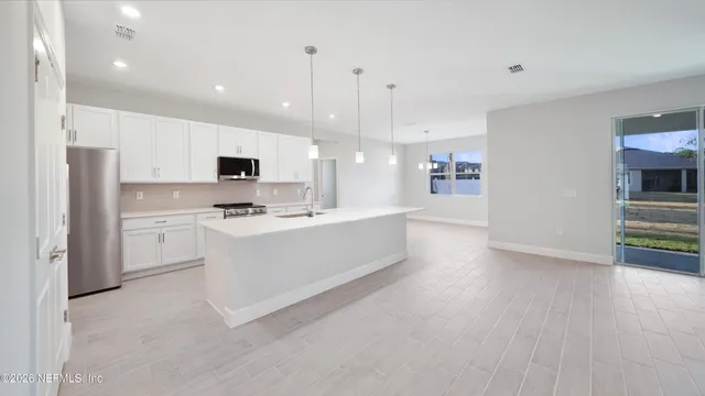 a large white kitchen with a refrigerator a stove top oven a sink and dishwasher with wooden floor