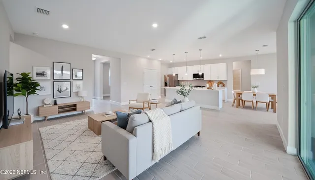 a living room with furniture white walls and kitchen view