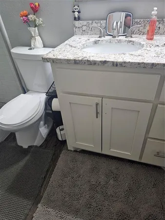 a bathroom with a granite countertop toilet sink and mirror