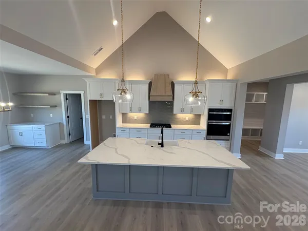 a kitchen with stainless steel appliances a kitchen island wooden floors and white cabinets