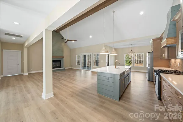 a living room with stainless steel appliances kitchen island granite countertop a stove and a wooden floors