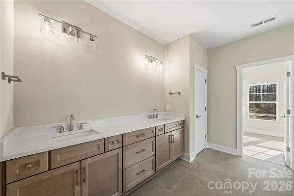 a spacious bathroom with a double vanity sink a large mirror and shower