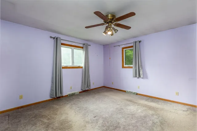 an empty room with window and ceiling fan