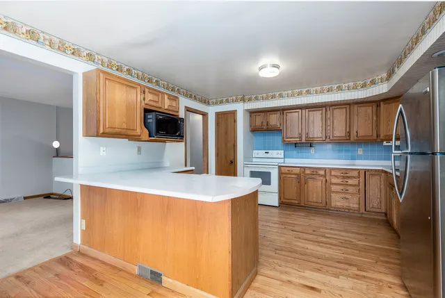 a kitchen with stainless steel appliances granite countertop a sink a stove and a wooden floors