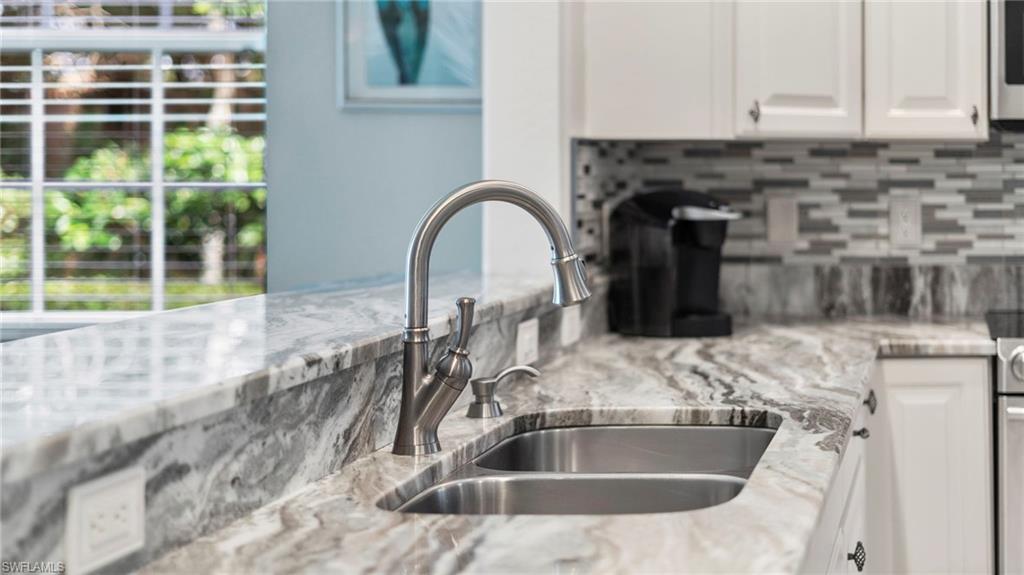 7876 Hawthorne Drive, Unit 1202 Naples, FL 34113 - Photo 18 of 48 Kitchen with tasteful backsplash, white cabinetry, sink, and light stone countertops