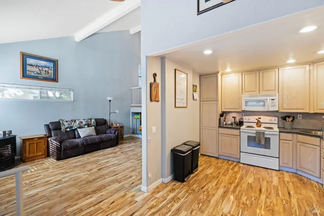 a kitchen with stainless steel appliances granite countertop a refrigerator a stove top oven a sink dishwasher and white cabinets with wooden floor