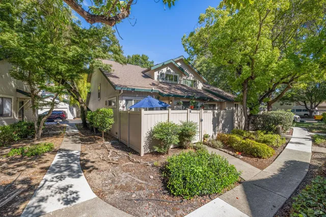 a view of a house with a small yard plants and large tree