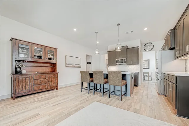 a large kitchen with cabinets wooden floor stainless steel appliances and dining table