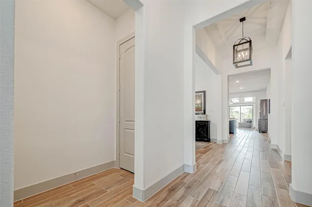 a view of a hallway with wooden floor and a bathroom