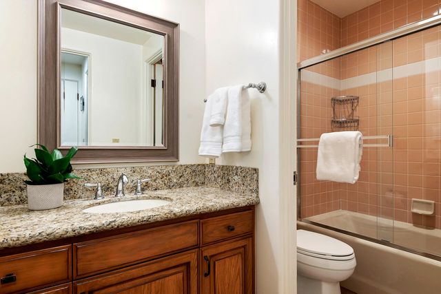 a bathroom with a granite countertop sink a toilet and shower
