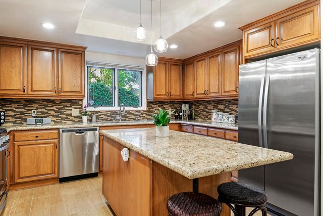 a kitchen with stainless steel appliances granite countertop a stove a sink dishwasher a refrigerator and cabinets with wooden floor