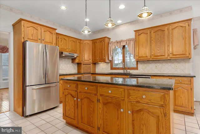 a kitchen with stainless steel appliances granite countertop a refrigerator a sink and a stove