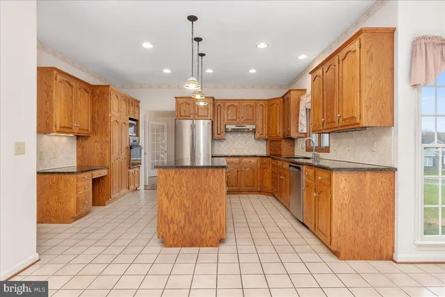 a kitchen with stainless steel appliances granite countertop a refrigerator a sink dishwasher and a stove with wooden cabinets