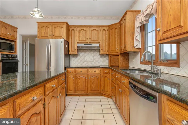 a kitchen with stainless steel appliances granite countertop a sink a stove and refrigerator