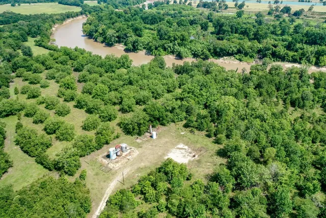 an aerial view of residential house with outdoor space and trees all around
