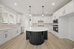 5423 Peach Gdn Way Manvel, TX 77578 - Photo 11 of 20 This kitchen features a spacious, modern design with white cabinetry, a large central island, stainless steel appliances, and wood flooring. Ample natural light enhances the bright and airy feel.