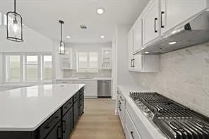 a large kitchen with granite countertop a large stove a sink dishwasher a refrigerator and white cabinets with wooden floor