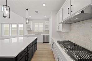 5423 Peach Gdn Way Manvel, TX 77578 - Photo 13 of 20 This kitchen is modern and spacious, featuring a large island with a sleek countertop, ample cabinetry, and a stainless steel gas cooktop. Pendant lights add elegance, while the light wood flooring and neutral tones create a bright, inviting atmosphere.