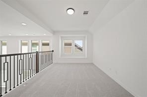 5423 Peach Gdn Way Manvel, TX 77578 - Photo 16 of 20 Spacious, bright loft area with carpeted floors, modern railing, and a large window providing natural light. Ideal for a cozy reading nook or additional living space.