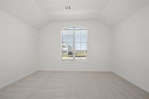 5423 Peach Gdn Way Manvel, TX 77578 - Photo 17 of 20 Bright and spacious room with high ceilings, neutral walls, and plush carpet. Features a large arched window offering ample natural light and a view of the neighborhood.