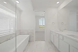 a spacious bathroom with a tub sink and mirror