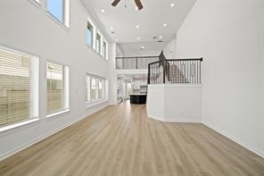 5423 Peach Gdn Way Manvel, TX 77578 - Photo 6 of 20 This bright, open-concept living space features high ceilings, large windows, and a modern wood floor. The room flows seamlessly into a kitchen area, and an elegant staircase leads to an upper level.