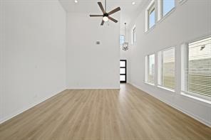 5423 Peach Gdn Way Manvel, TX 77578 - Photo 7 of 20 This photo showcases a spacious, bright room with high ceilings and large windows, allowing plenty of natural light. It features modern light fixtures, a ceiling fan, and wood flooring, creating a contemporary and airy atmosphere.