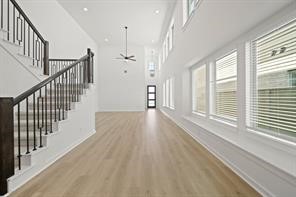 5423 Peach Gdn Way Manvel, TX 77578 - Photo 9 of 20 This photo showcases a spacious, bright living area with high ceilings, large windows, and light wood flooring. The modern staircase features dark railings, adding a touch of elegance.