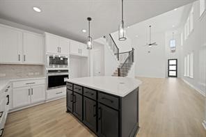 5423 Peach Gdn Way Manvel, TX 77578 - Photo 10 of 20 This modern kitchen features a spacious open layout with a large island, sleek white cabinetry, and contrasting black lower cabinets. The space is bright with ample natural light, high ceilings, and stylish pendant lighting.