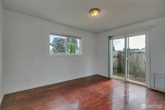 an empty room with wooden floor and windows