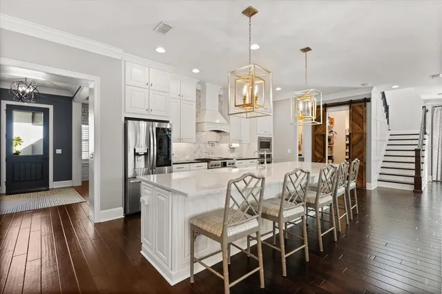 a view of a dining room and livingroom with furniture wooden floor kitchen chandelier