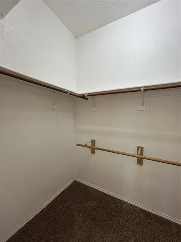 an empty room with a chandelier fan and windows