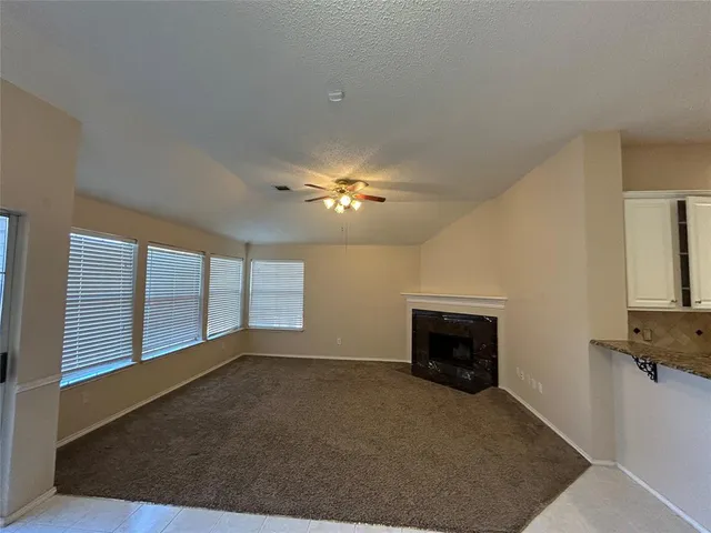 an empty room with windows and fireplace