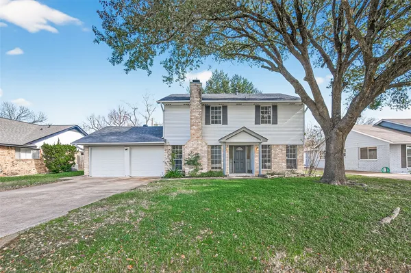 a front view of a house with a yard and trees
