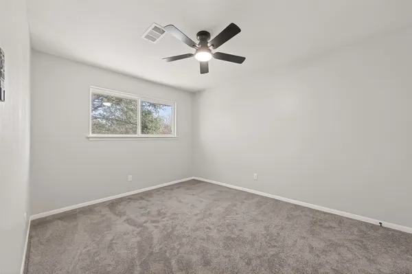an empty room with a window and a fan