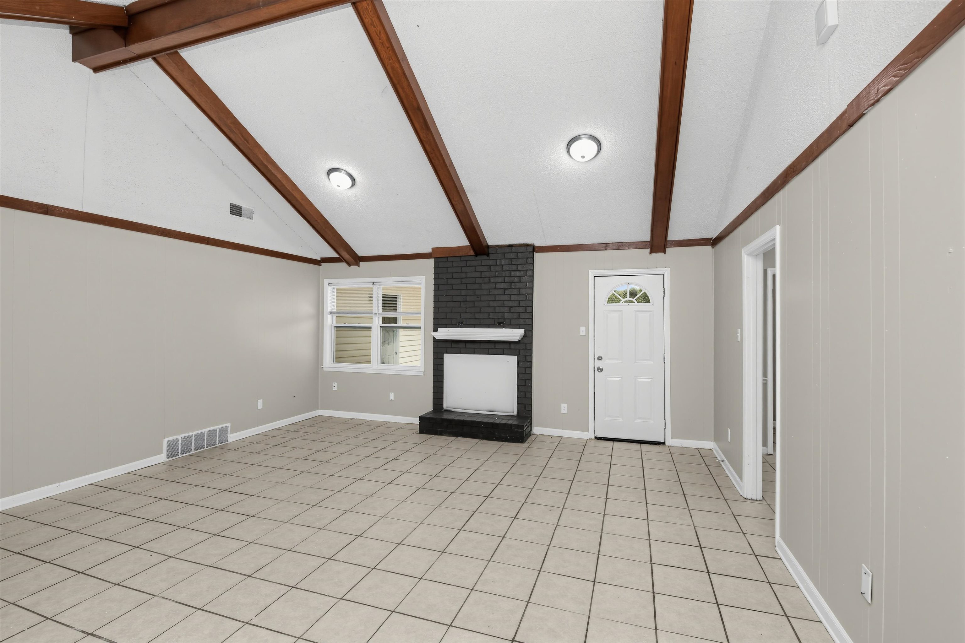 6350 Midsummer Way Memphis, TN 38115 - Photo 5 of 21 Vaulted ceiling with exposed wood beams, tile flooring, and a black brick fireplace with a white mantel