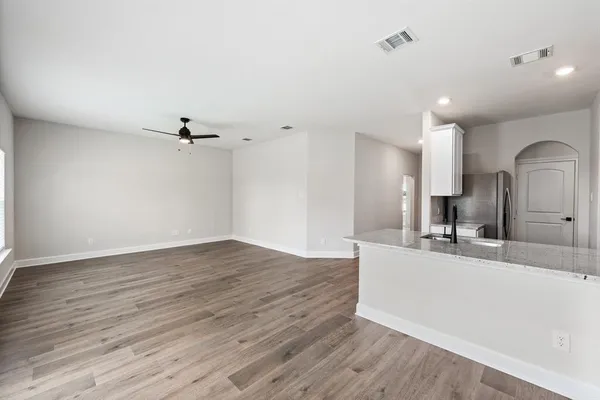 a large kitchen with stainless steel appliances kitchen island a stove a refrigerator with white cabinets and wooden floor
