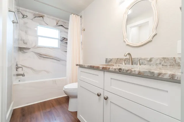 a bathroom with a granite countertop sink toilet and shower