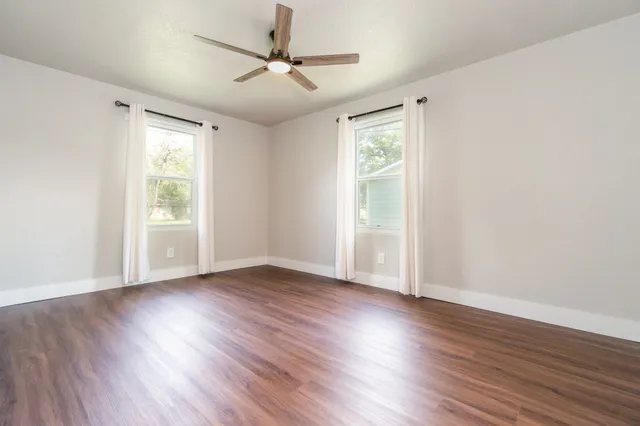 a view of an empty room with wooden floor and a window