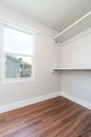 a view of an empty room with wooden floor and a window