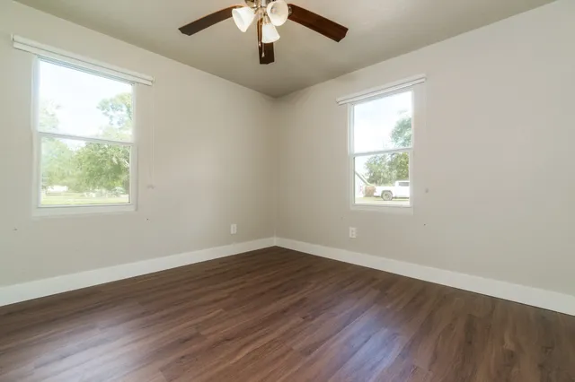 a view of an empty room with wooden floor and a window