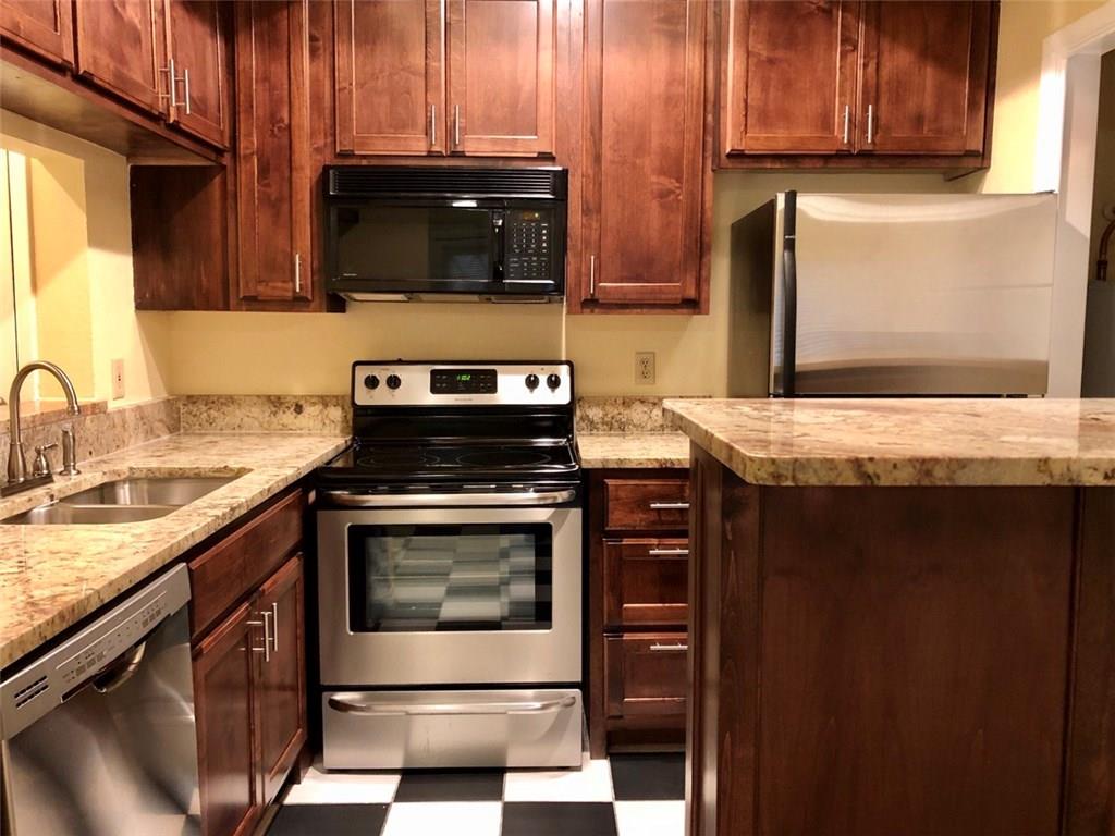 806 West 24th Street, Unit 107 Austin, TX 78705 - Photo 2 of 7 a kitchen with stainless steel appliances granite countertop wooden cabinets and a stove top oven