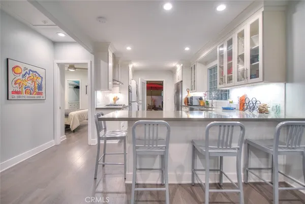 a kitchen with stainless steel appliances granite countertop a dining table chairs and a refrigerator