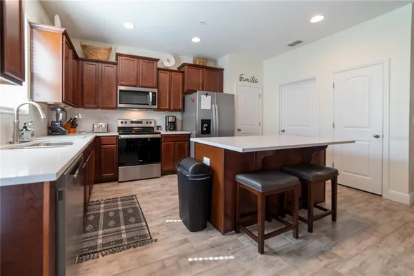 a kitchen with stainless steel appliances granite countertop a stove top oven a sink dishwasher a dining table and chairs with wooden floor