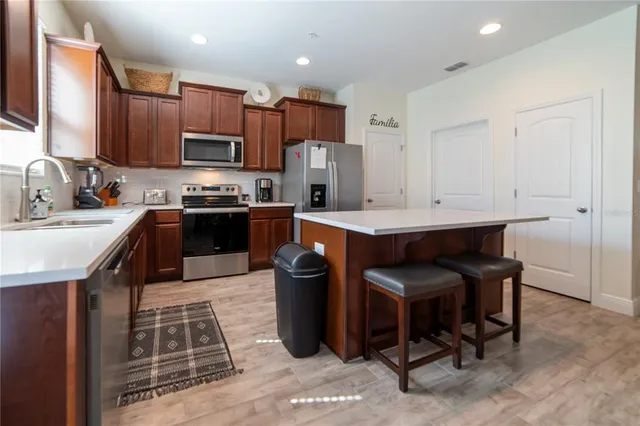 a kitchen with stainless steel appliances granite countertop a stove top oven a sink dishwasher a dining table and chairs with wooden floor